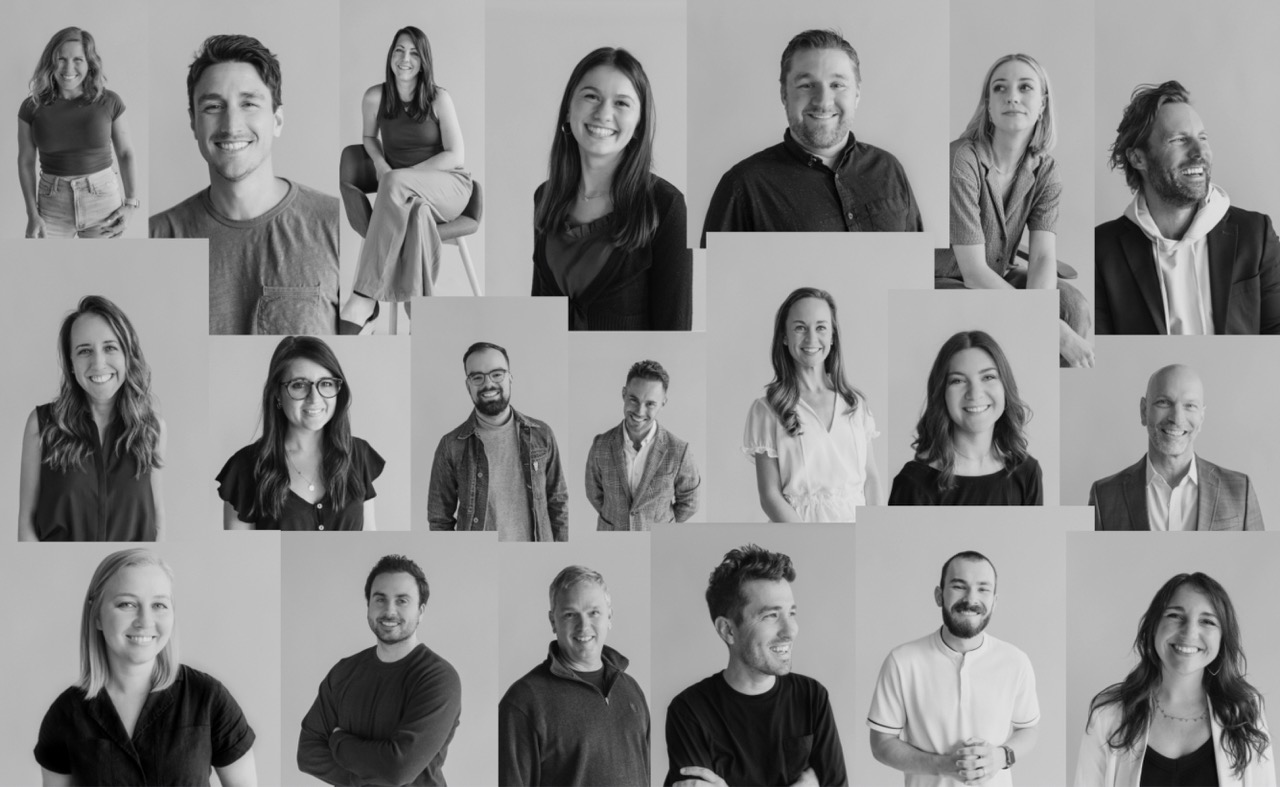 A collage of 20 diverse people, men and women, pose individually against a plain background, all smiling or looking friendly. The photo is in black and white and captures different expressions and body language.